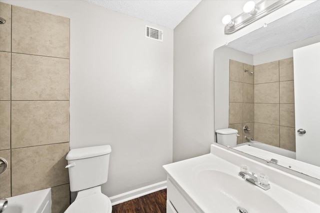 bathroom with wood finished floors, toilet, shower / washtub combination, a textured ceiling, and baseboards