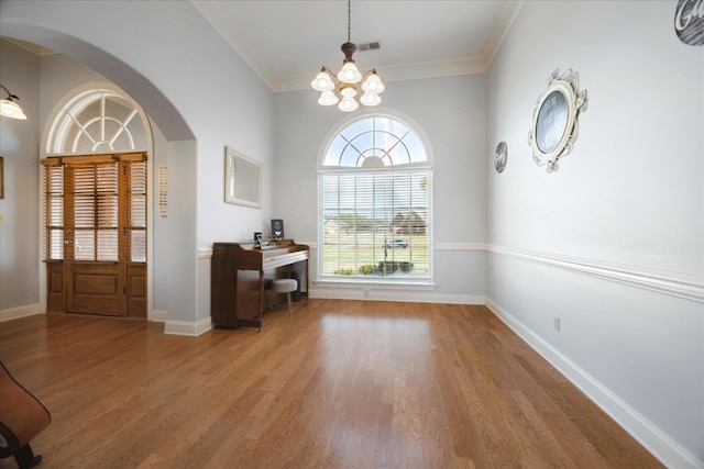 entryway featuring arched walkways, light wood-type flooring, plenty of natural light, and crown molding