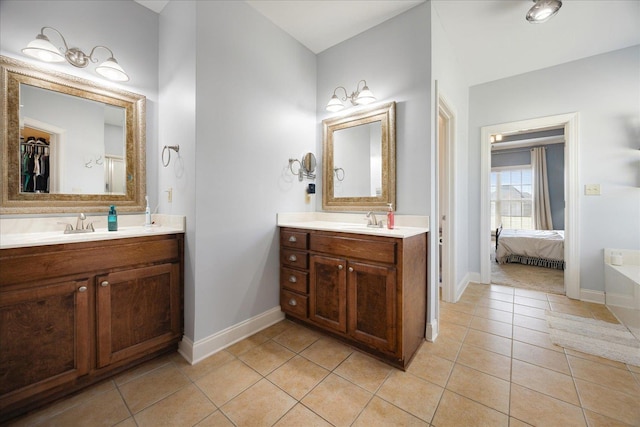 ensuite bathroom with tile patterned floors, baseboards, and two vanities
