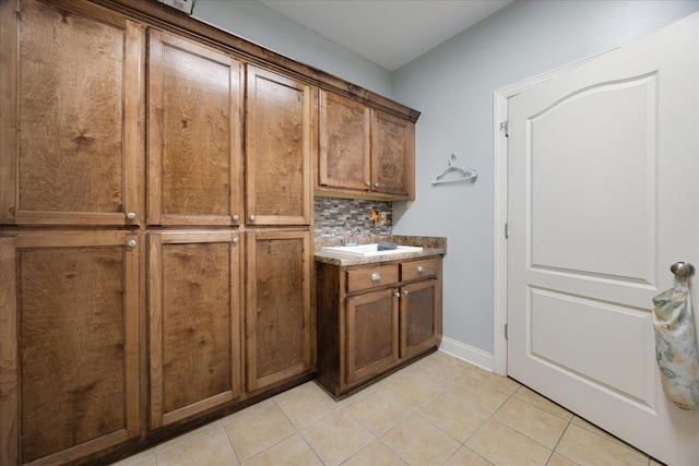 bar area with a sink, light tile patterned flooring, backsplash, and baseboards