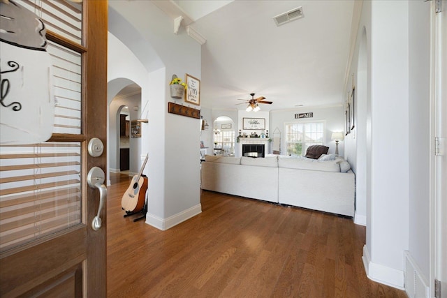 hall featuring arched walkways, dark wood-style flooring, ornamental molding, and baseboards