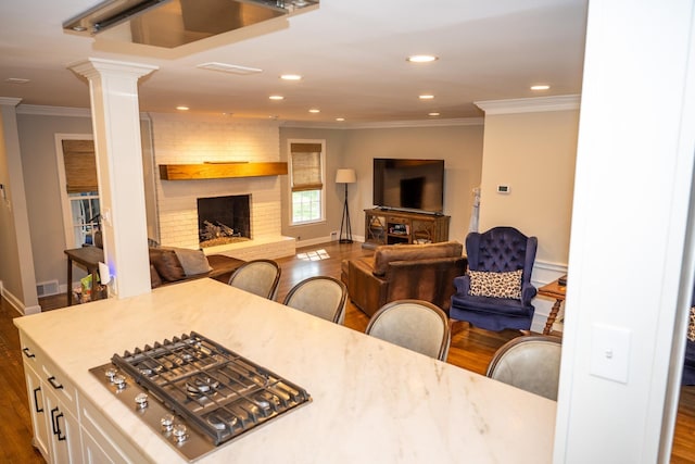 dining room with a brick fireplace, dark wood finished floors, ornamental molding, decorative columns, and recessed lighting