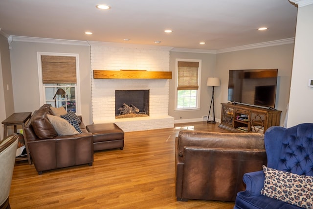 living room with wood finished floors, crown molding, a brick fireplace, recessed lighting, and baseboards