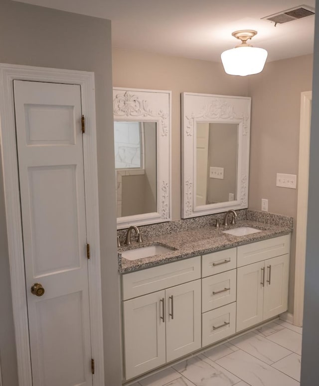 bathroom featuring marble finish floors and double vanity