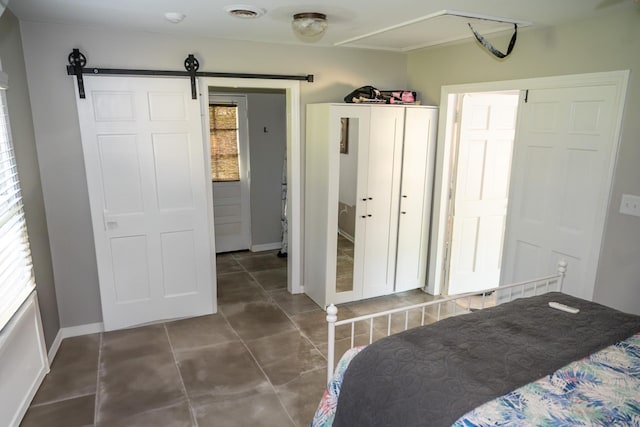 bedroom with a barn door, multiple windows, baseboards, and tile patterned flooring