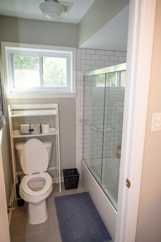 full bathroom featuring tile patterned floors, bath / shower combo with glass door, toilet, and baseboards