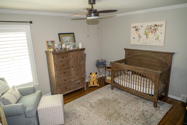 bedroom featuring wood finished floors, ornamental molding, a nursery area, multiple windows, and baseboards