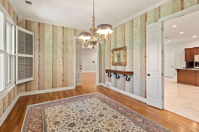 dining space with wallpapered walls, a chandelier, wood finished floors, crown molding, and baseboards
