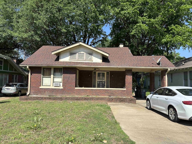 view of front facade with a front lawn, brick siding, covered porch, and a chimney