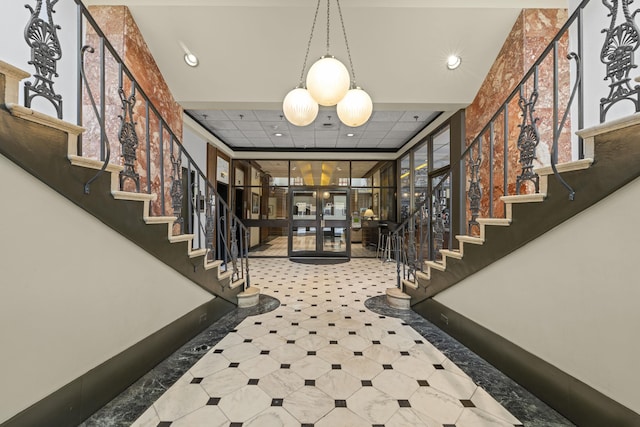 foyer entrance with stairway, inlaid floor details, recessed lighting, french doors, and a drop ceiling