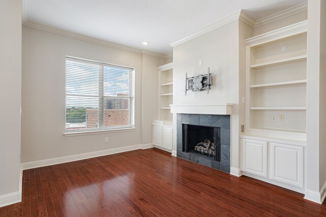 510 Cityhouse Ct Unit 406, Memphis, TN 38103 - unfurnished living room with baseboards, a tiled fireplace, dark wood-style floors, built in features, and ornamental molding