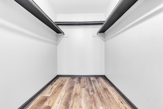 walk in closet with wood finished floors