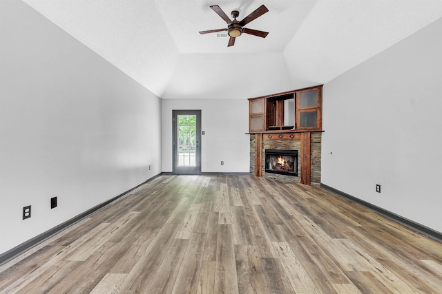 unfurnished living room with ceiling fan, a lit fireplace, light wood finished floors, baseboards, and high vaulted ceiling