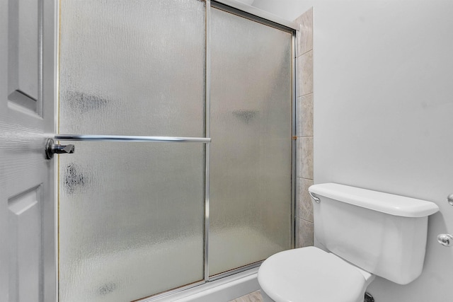 full bathroom with a stall shower and toilet