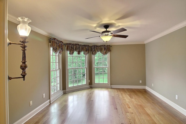 empty room with ornamental molding, light wood finished floors, a ceiling fan, and baseboards