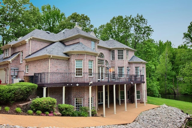 rear view of property with brick siding, a patio, a wooden deck, and a chimney
