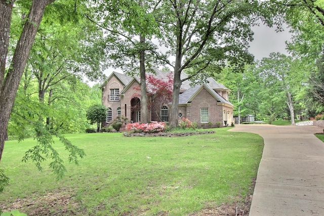 view of front facade featuring brick siding, a front yard, and concrete driveway