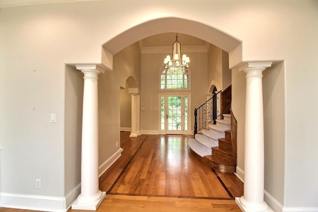 entrance foyer with arched walkways, wood finished floors, stairway, ornamental molding, and baseboards