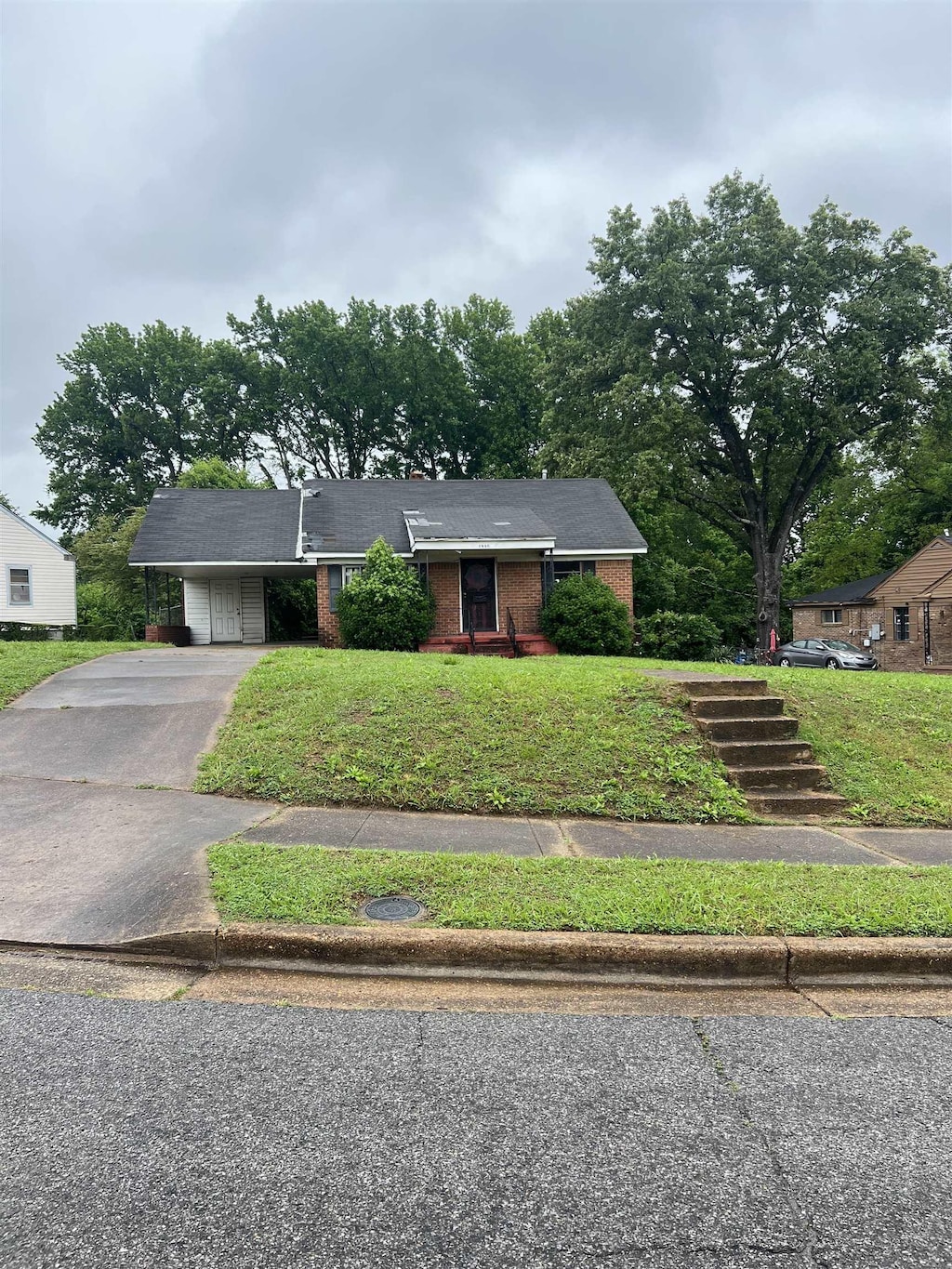 ranch-style house with brick siding, asphalt driveway, a front lawn, and a carport
