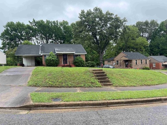ranch-style house featuring brick siding, asphalt driveway, a carport, and a front yard