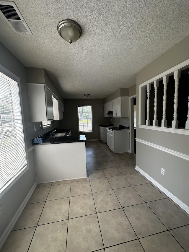 2980 Ridgeway Dr, Memphis, TN 38115 - kitchen with dark countertops, a textured ceiling, a sink, white cabinetry, and a peninsula