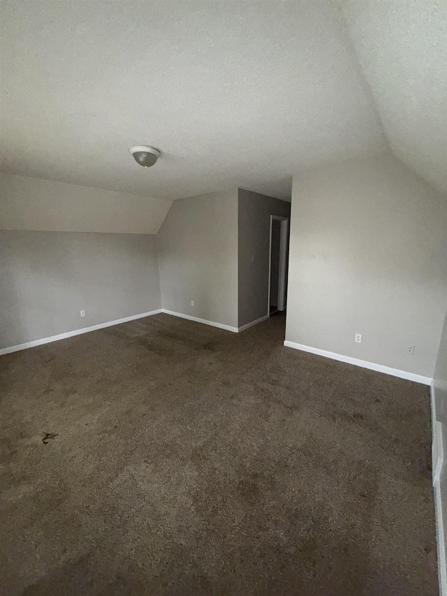 2980 Ridgeway Dr, Memphis, TN 38115 - additional living space featuring vaulted ceiling, baseboards, dark colored carpet, and a textured ceiling