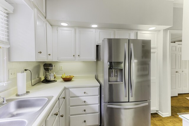 kitchen with stainless steel fridge with ice dispenser, a sink, white cabinetry, light countertops, and light wood finished floors