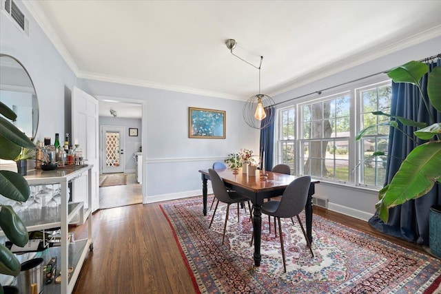 dining space featuring dark wood finished floors, baseboards, and ornamental molding