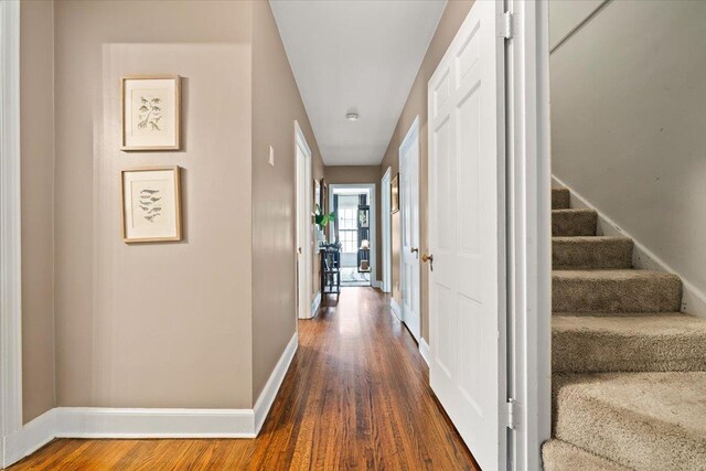 hall featuring baseboards, dark wood finished floors, and stairs