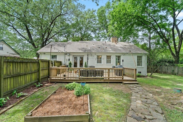 rear view of house with a chimney, a vegetable garden, a deck, and crawl space