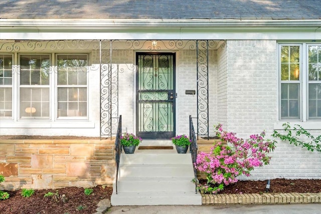 entrance to property with brick siding and roof with shingles