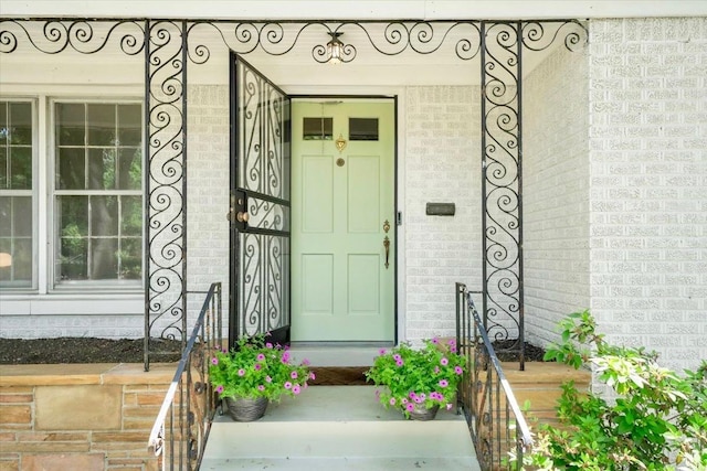 property entrance featuring a porch and brick siding