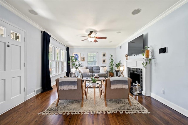 living area featuring wood finished floors, ceiling fan, baseboards, ornamental molding, and a tile fireplace