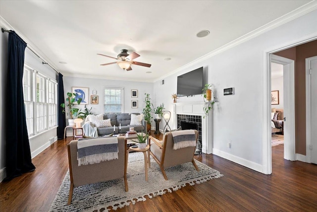 living room with baseboards, ceiling fan, wood finished floors, a fireplace, and crown molding