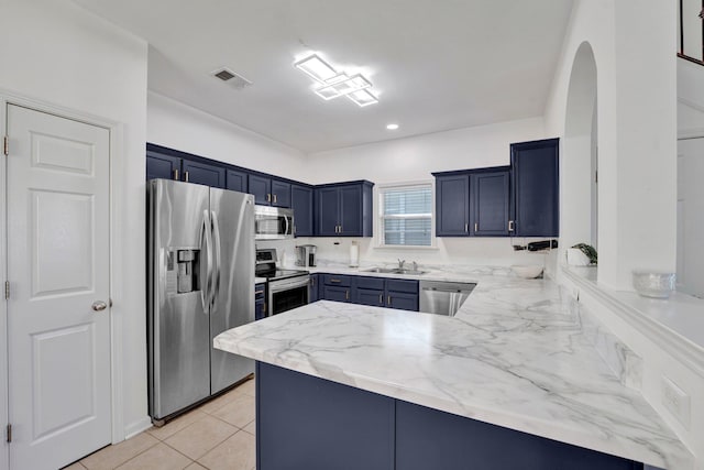 kitchen with appliances with stainless steel finishes, a sink, blue cabinetry, a peninsula, and arched walkways