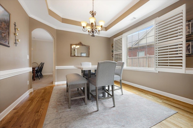 1685 Jennings Mill Ln, Collierville, TN 38017 - dining area featuring arched walkways, wood finished floors, a chandelier, crown molding, and a raised ceiling