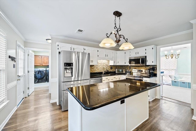 8606 Meadow Green Dr, Memphis, TN 38016 - kitchen featuring stainless steel appliances, washer and clothes dryer, a sink, a chandelier, and wood finished floors