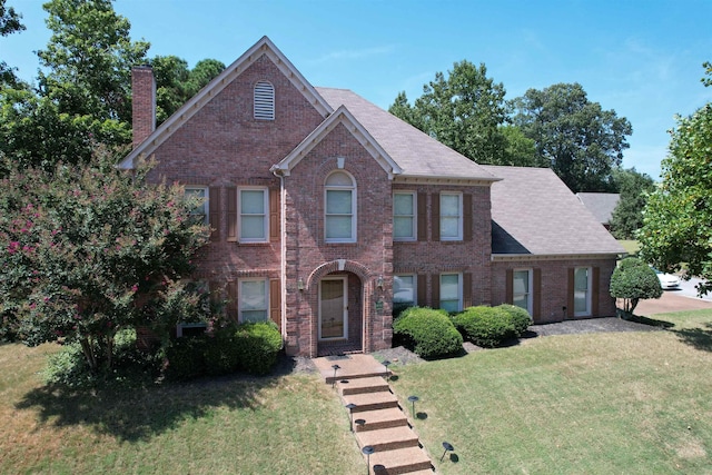 8606 Meadow Green Dr, Memphis, TN 38016 - view of front of home with brick siding, a chimney, a front yard, and a shingled roof