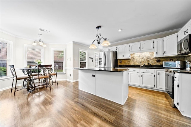 8606 Meadow Green Dr, Memphis, TN 38016 - kitchen featuring appliances with stainless steel finishes, a chandelier, dark countertops, ornamental molding, and white cabinetry