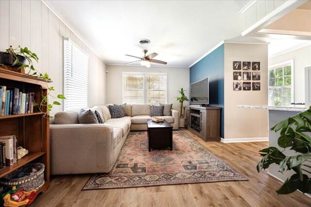 living room featuring ornamental molding, wood finished floors, a ceiling fan, and baseboards