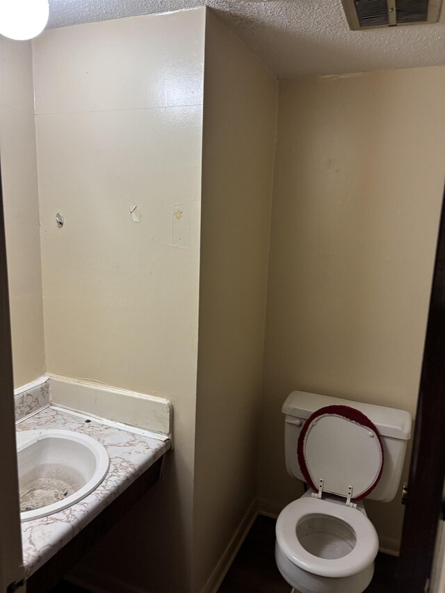bathroom featuring a textured ceiling, toilet, vanity, and baseboards