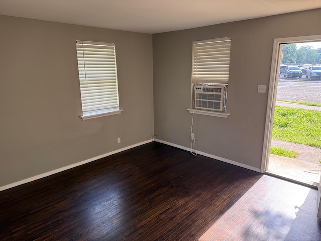 spare room featuring dark wood-type flooring, cooling unit, and baseboards