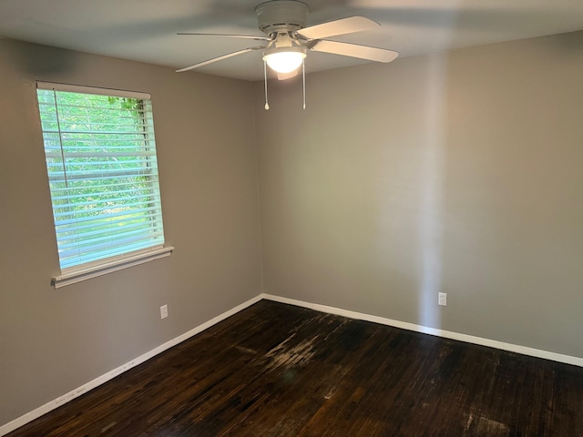 empty room featuring ceiling fan, dark wood-style floors, and baseboards