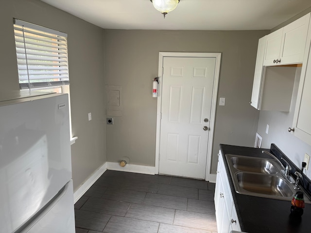 washroom with hookup for an electric dryer, a sink, baseboards, and tile patterned flooring
