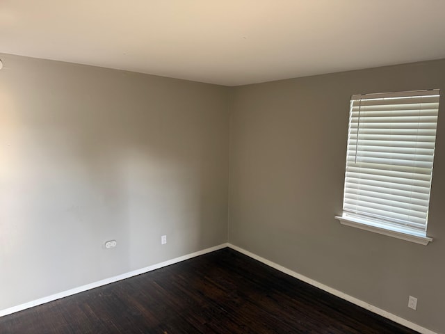 unfurnished room with baseboards and dark wood-style flooring