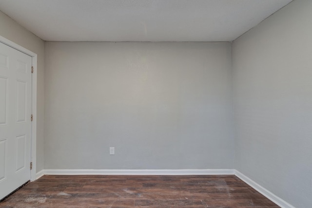 spare room with dark wood-style flooring and baseboards