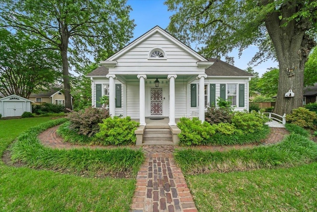 greek revival house with a porch, a storage shed, and an outbuilding