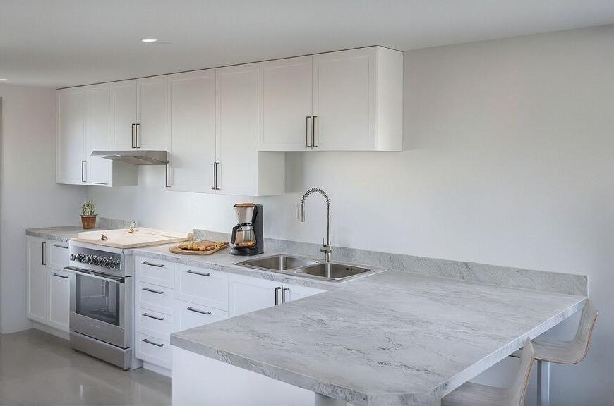 1648 Gill Ave, Memphis, TN 38106 - kitchen featuring stainless steel range, a sink, white cabinets, under cabinet range hood, and a peninsula