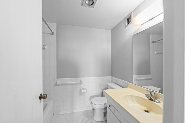 bathroom featuring toilet, tile walls, vanity, tile patterned flooring, and shower / washtub combination