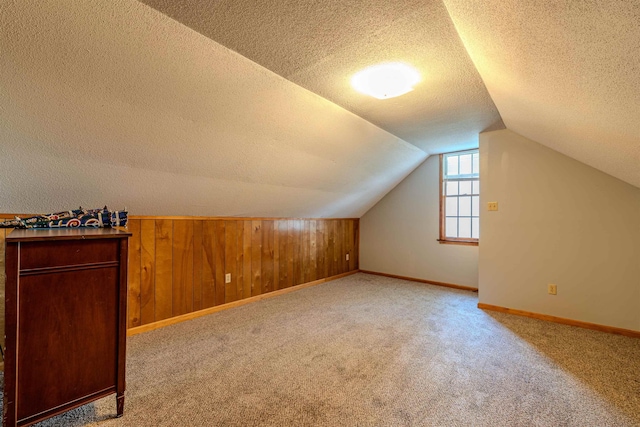 bonus room featuring a textured ceiling, carpet floors, lofted ceiling, and baseboards